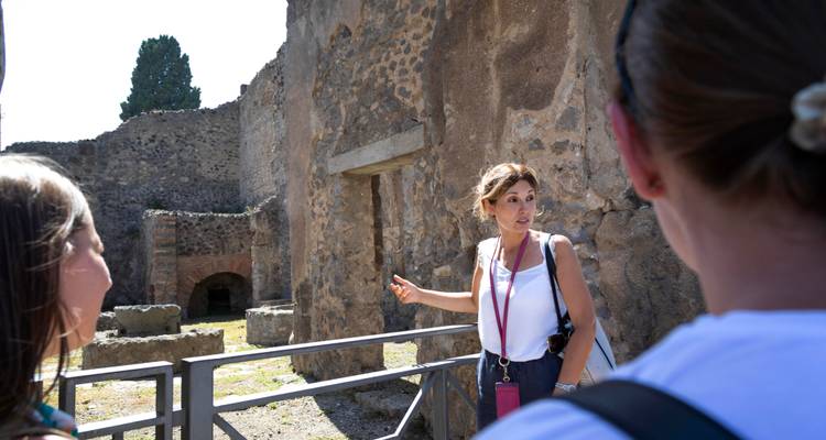 Guía explicando las murallas antiguas de Pompeya a visitantes atentos dentro del sitio arqueológico.
