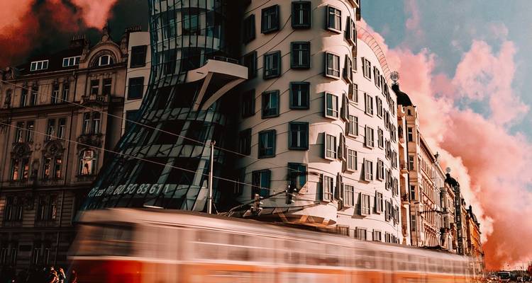 Moderne Architektur mit vorbeifahrender Straßenbahn, dynamischer Himmel.