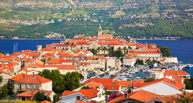 A coastal town with red-tiled roofs and a church tower.