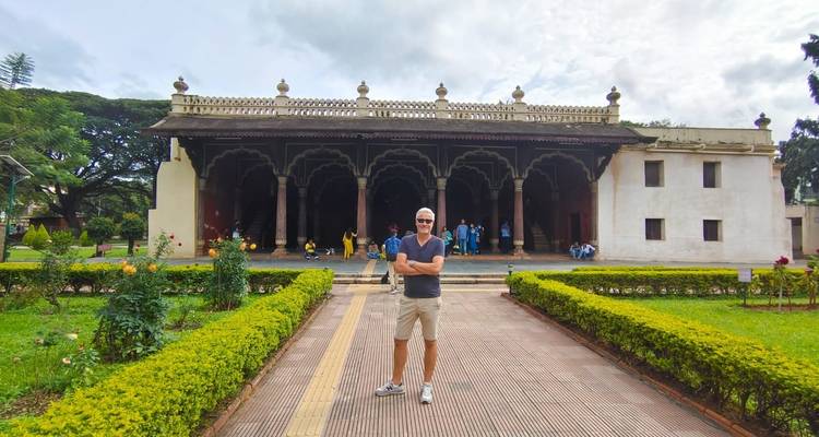 Man poseert voor een historisch gebouw met boogvormige architectuur.