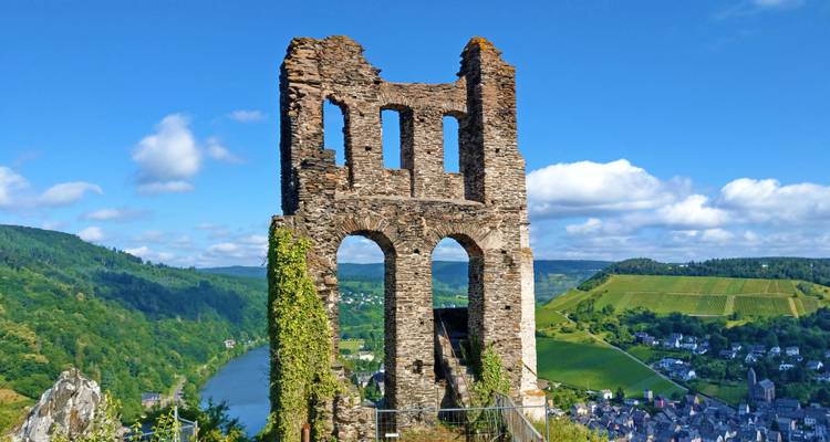 Hohe Steinruine mit Bogenfenstern steht auf einer Klippe über dem Flusstal.
