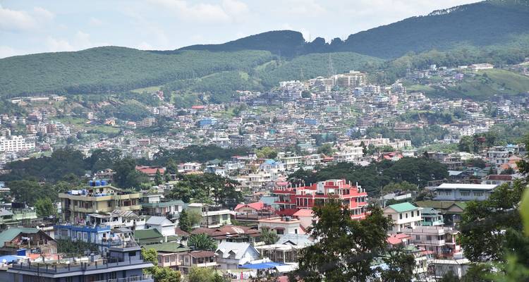 Panoramablick auf eine hügelige Stadtlandschaft mit Grün.