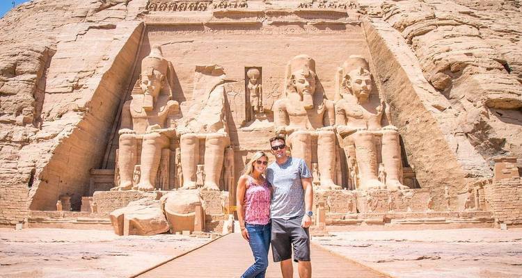 Couple posing in front of the Abu Simbel temple with large seated statues.