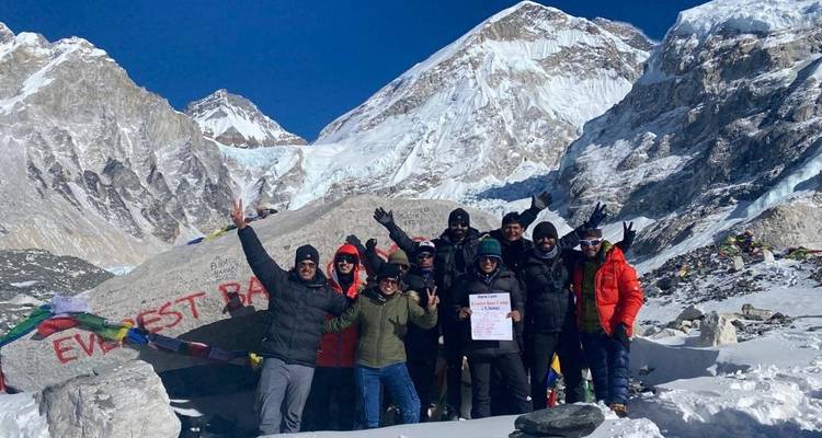 Group celebrating at Everest Base Camp with snowy mountains.