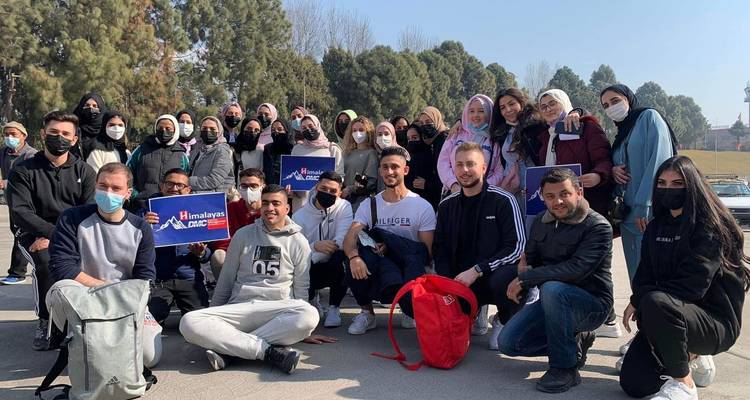 Large group of people posing outdoors with signs.