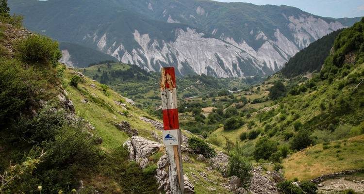 Tal mit einem Wegweiser und fernen Bergen.