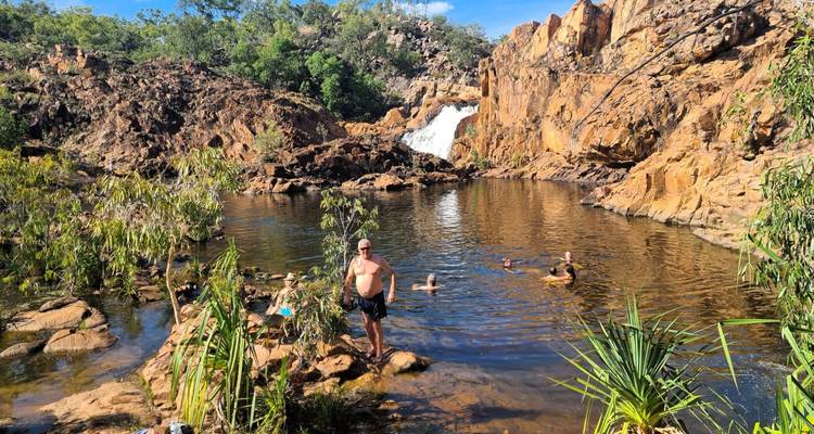 Piscine naturelle de roche sous une petite cascade où les voyageurs nagent et se tiennent parmi le grès accidenté