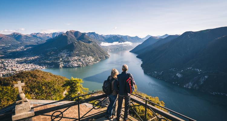 Couple admirant une vue panoramique sur un lac avec les montagnes environnantes.