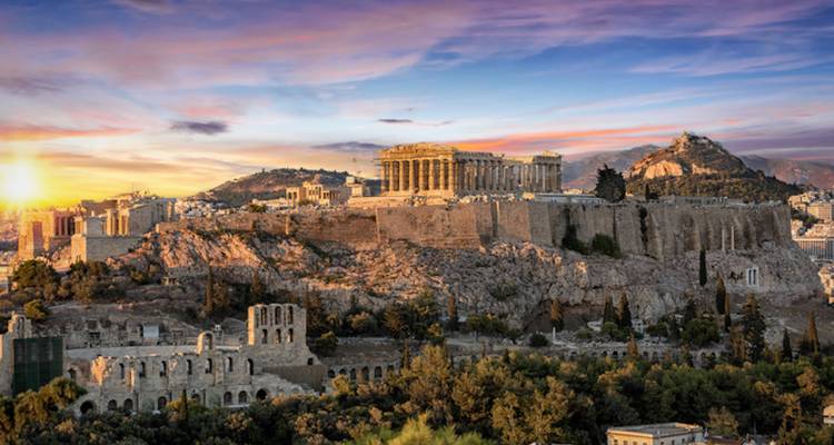 Sunset illuminates the Acropolis and Parthenon atop rocky hill with Athens city spreading below.