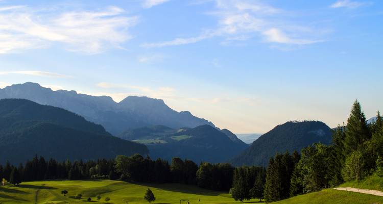 Eine weite grüne Landschaft mit Bergen in der Ferne unter einem klaren Himmel.