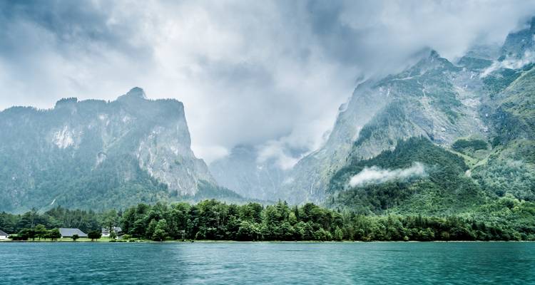 Ein dramatischer Blick auf nebelverhüllte Berge über einem See.