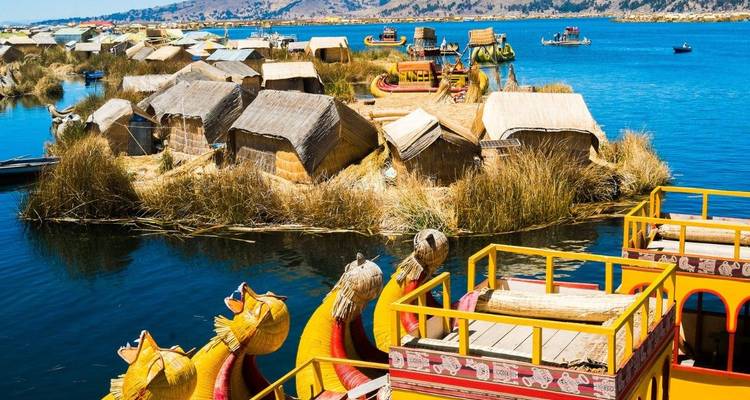 Floating reed houses and colorful boats on a lake.