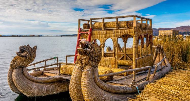 Detail of a reed boat on a lake with mountains in the distance.
