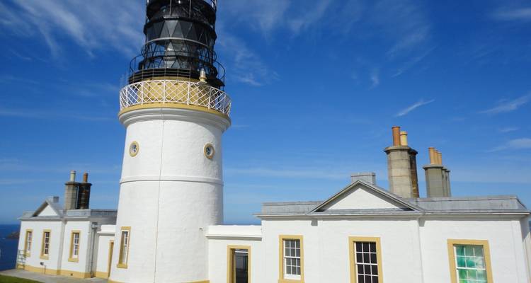 Phare blanc avec un ciel bleu clair.