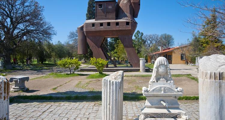 Réplica del Caballo de Troya y ruinas antiguas bajo un cielo azul despejado.
