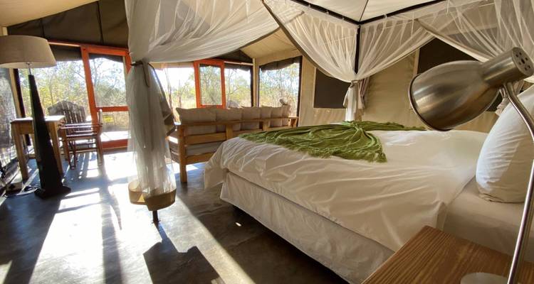Een luxueus tentinterieur met een bed omringd door gaas.