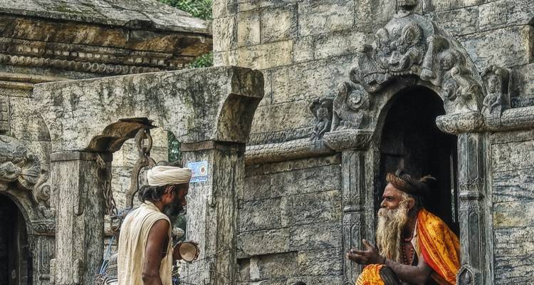 Twee mannen in gesprek voor ingewikkeld gebeeldhouwde stenen gebouwen.