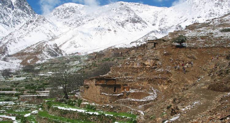 Terrassenfelder an einem Berghang, teilweise mit Schnee bedeckt.