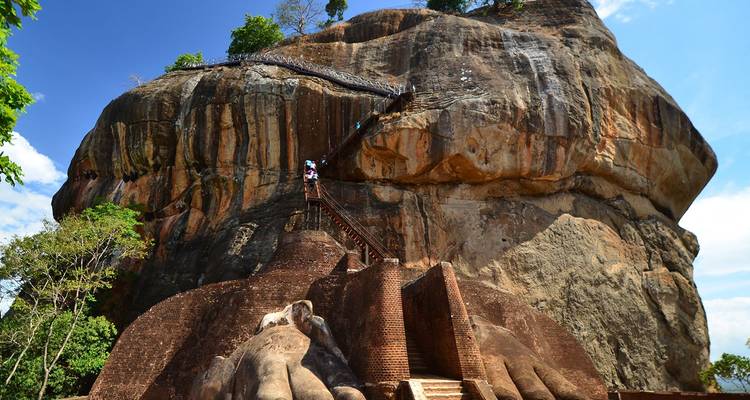 Visitors ascending the steep stairway on the face of Sigiriya Rock Fortress amid lush jungle scenery.