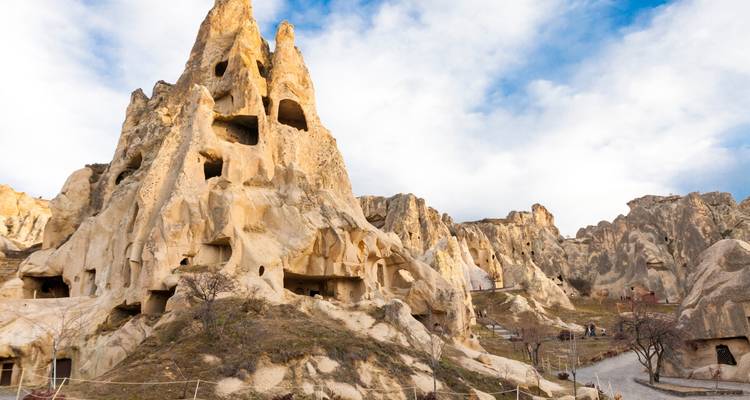 Formaciones rocosas con viviendas en cuevas bajo un cielo azul.