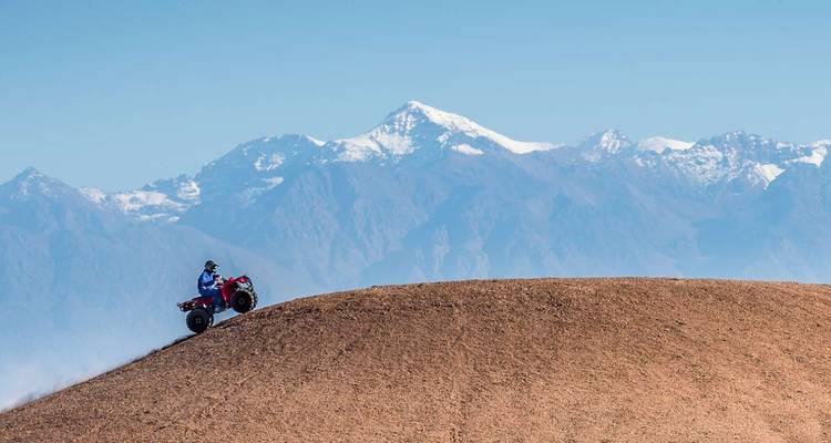 Persoon op een quad die een woestijnheuvel beklimt.