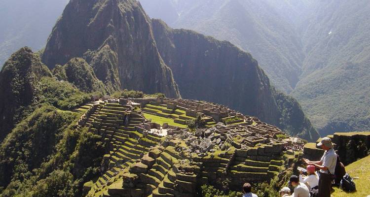 Panoramisch zicht op Machu Picchu met toeristen die aan het verkennen zijn.