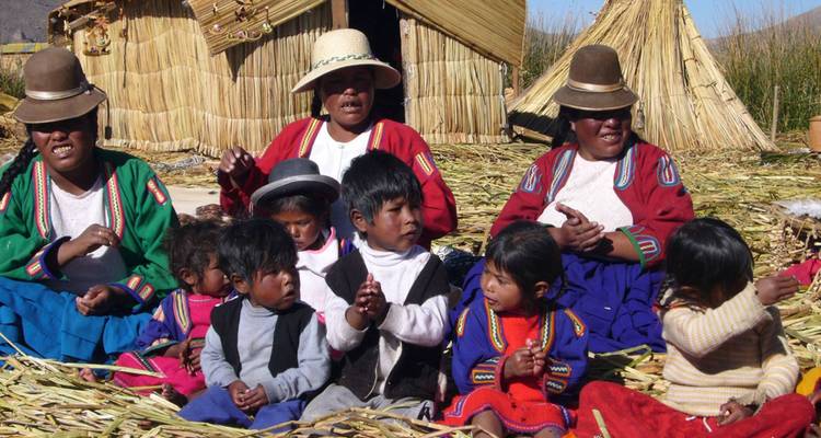 Een groep mensen in traditionele kleding zittend op een rietplatform.