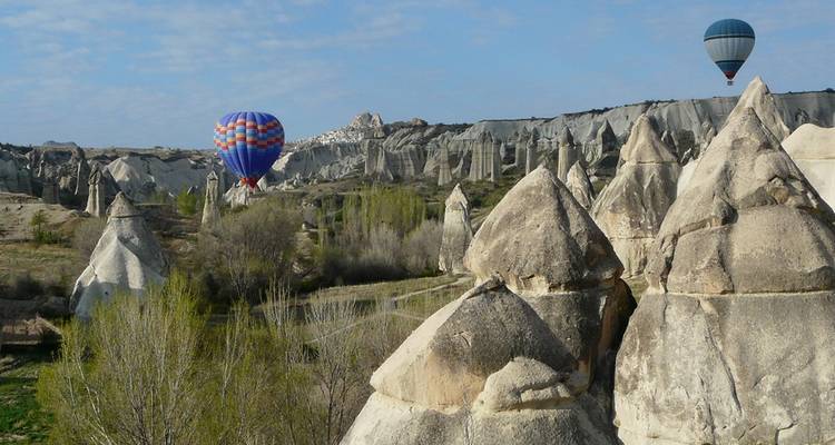 Unique rock formations with hot air balloons in the sky.