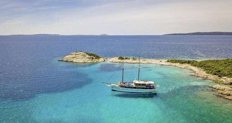 Velero cerca de una pequeña isla en aguas cristalinas.
