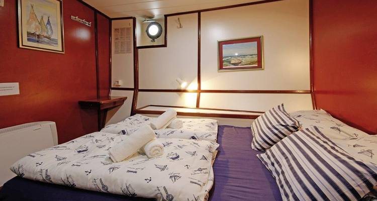 Camarote con cama doble y decoración de temática náutica en un barco.