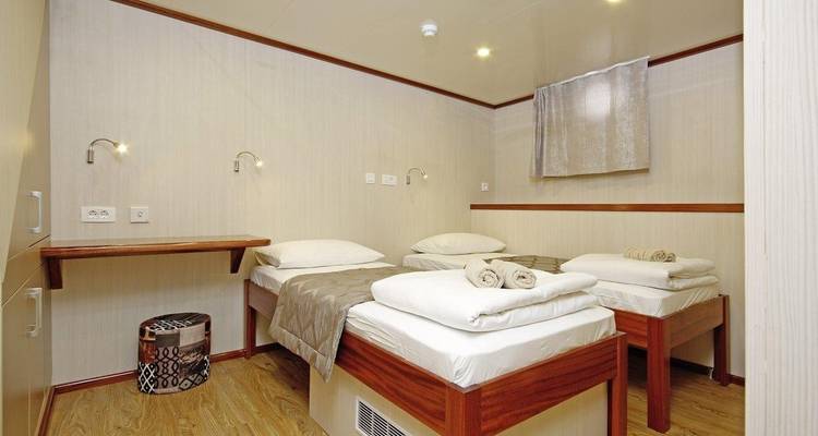 Camarote con dos camas individuales y decoración sencilla en un barco.