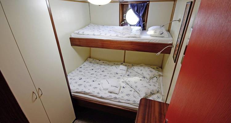 Kleine hut met stapelbedden op een boot.