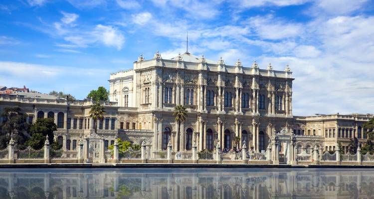 Dolmabahçe-Palast-Fassade mit Spiegelung im Wasser unter blauem Himmel.