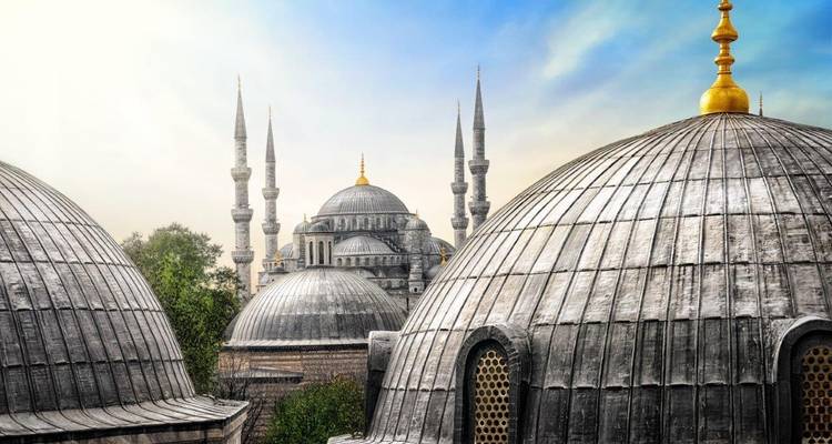 Vue d'une mosquée avec plusieurs dômes et minarets.