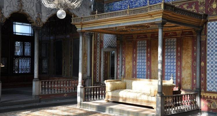 Intérieur d'une salle historique richement décorée avec des colonnes et un canapé.