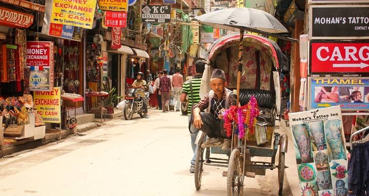 Person, die auf einer Rikscha in einer belebten Marktstraße sitzt.
