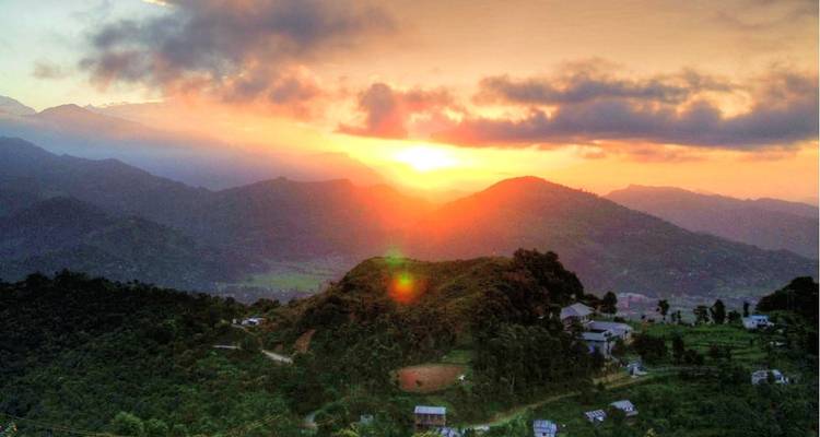 Sonnenuntergang über sanften Hügeln und einem kleinen Dorf.