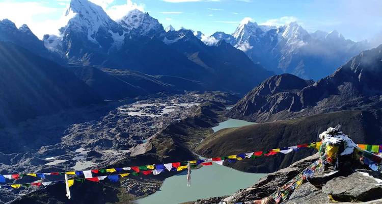 Gebetsfahnen mit Blick auf eine Bergkette und türkisfarbene Seen.