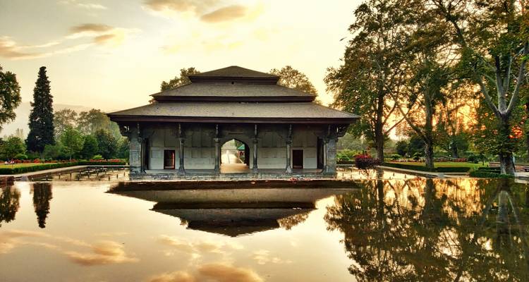 Schöner Pavillon in einem Garten mit einem Wasserbecken bei Sonnenuntergang.