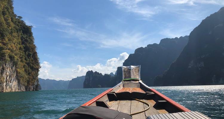 Ein Boot auf einem See, umgeben von Klippen in einer tropischen Umgebung.