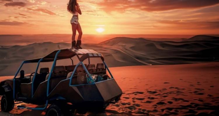 Persona de pie en un buggy de dunas al atardecer, contemplando el desierto