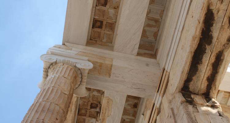 Detalle arquitectónico de cerca de una columna de mármol y un techo con casetones de un antiguo templo griego