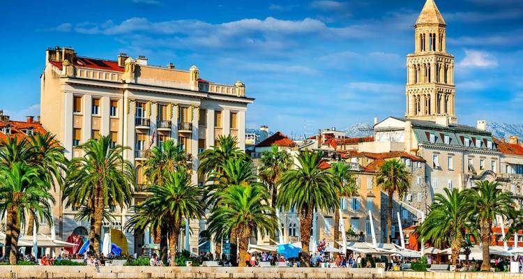 Eine Uferpromenade-Stadtlandschaft mit Palmen und historischer Architektur.