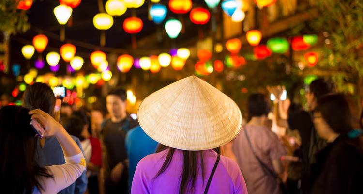 Belebte Straßenszene mit bunten Laternen, die nachts hängen.