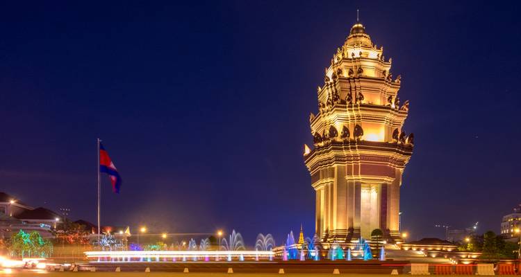 Verlicht monument bij nacht met een nationale vlag en fonteinen.
