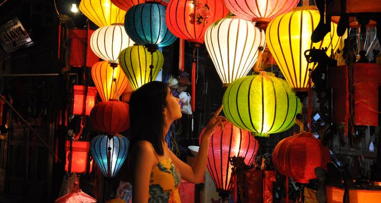 Een persoon die interacteert met een levendige vertoning van kleurrijke lantaarns in een marktomgeving.