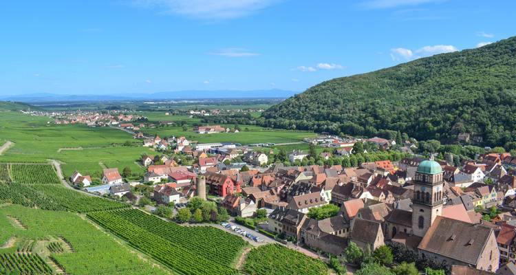 Vue panoramique d'un village français entouré de vignobles et de champs.