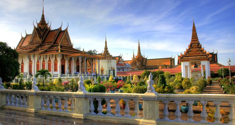 Khmer temple complex with blooming gardens under a clear sky.