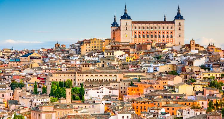 Elevated view of Toledo’s densely packed historic houses crowned by the imposing Alcázar at sunset.