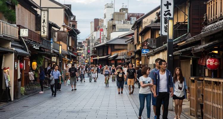 Scène de rue animée dans un quartier traditionnel japonais avec des boutiques et des passants.